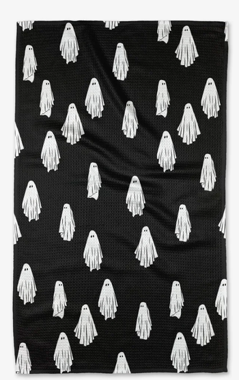 A tea towel in black featuring a white ghost pattern