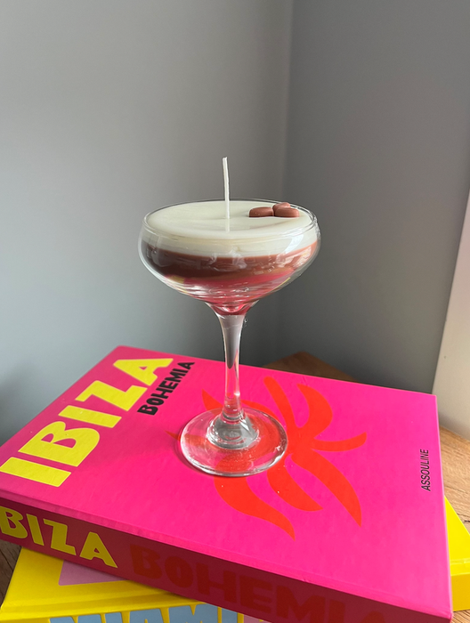 A candle crafted to resemble an espresso martini in a stylish stemmed glass.