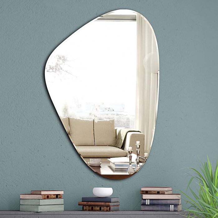 The mirror mounted on a wall above a table filled with stacked books