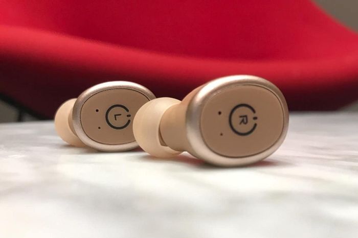 A close-up of the reviewer's gold earbuds, clearly marked for left and right ears.