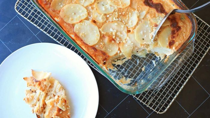 A serving of potato au gratin from a casserole dish, with a spoonful plated.