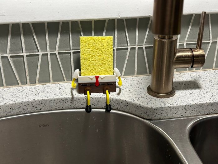 SpongeBob SquarePants sponge holder placed on a countertop next to a kitchen sink and faucet