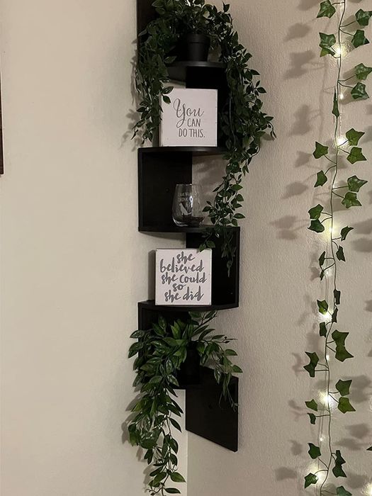 The black shelf adorned with quote canvases and faux vines