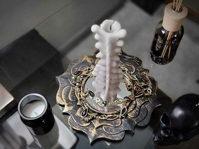 A close-up shot of a spine-shaped candle resting on a table surrounded by Halloween decorations.