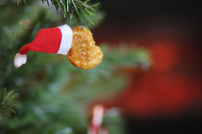 The Santa hat chicken nugget ornament, now hanging from a tree, ready to bring some holiday humor.