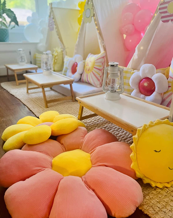 Large pink and yellow pillows spread across the floor in a child's bedroom.
