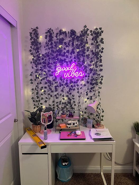 The neon sign mounted above a desk, surrounded by artificial vines on the wall