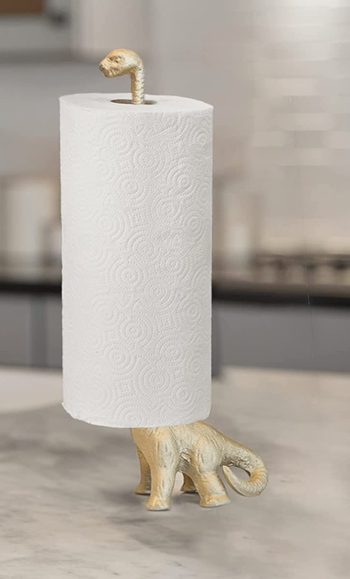 A dinosaur-shaped holder with a paper towel roll perched on its elongated neck