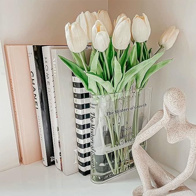 The clear vase sitting on a table with white tulips inside