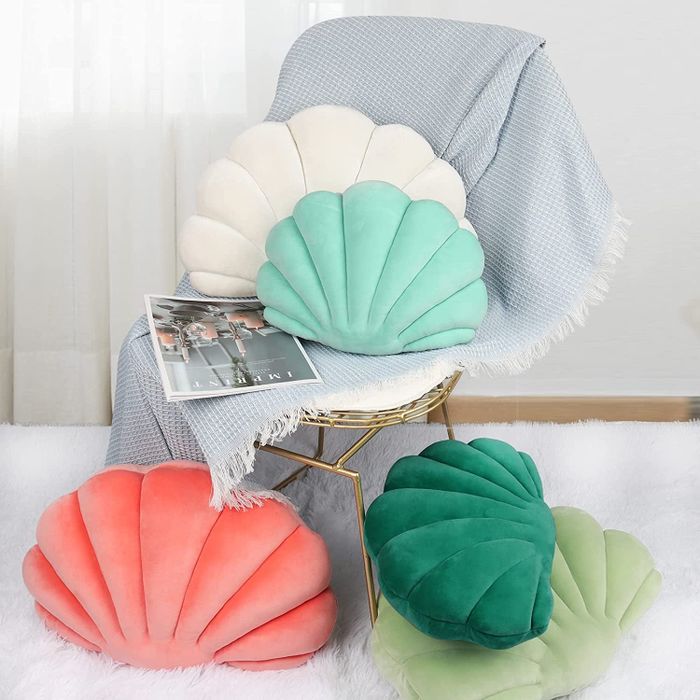 A variety of colorful pillows arranged on a chair and scattered on the floor nearby