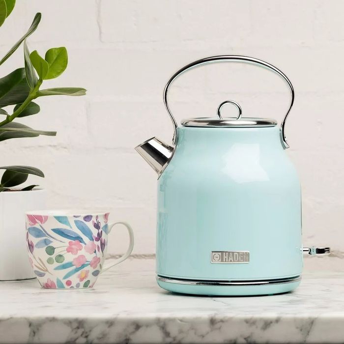 The blue electric tea kettle featuring a round handle and a small spout, placed on a kitchen counter