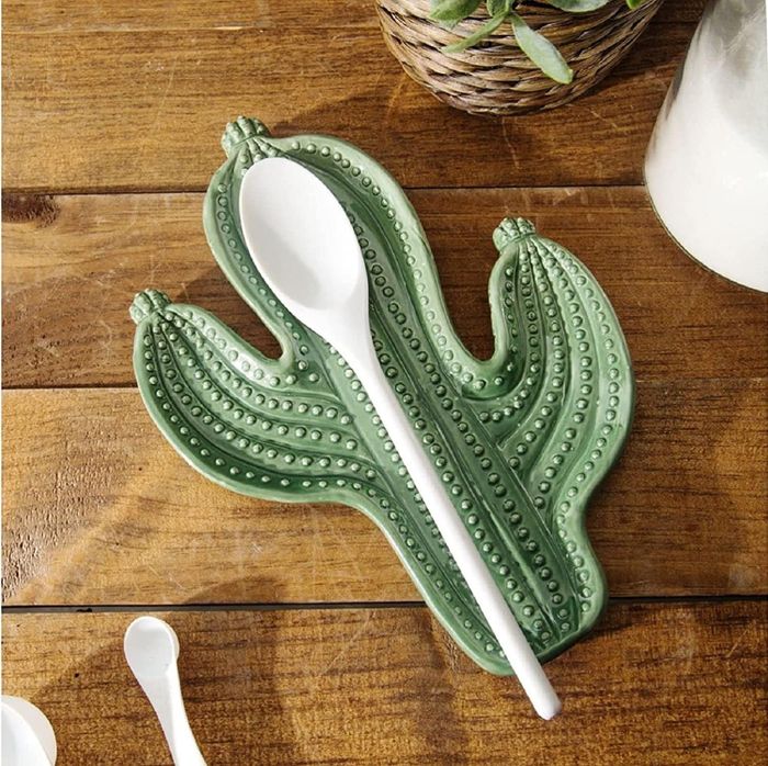 A wooden spoon casually resting on a green cactus spoon rest, adding a fun touch to the kitchen.