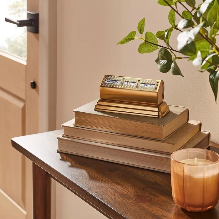 The brass manual calendar resting atop a stack of books, adding vintage charm to any space.