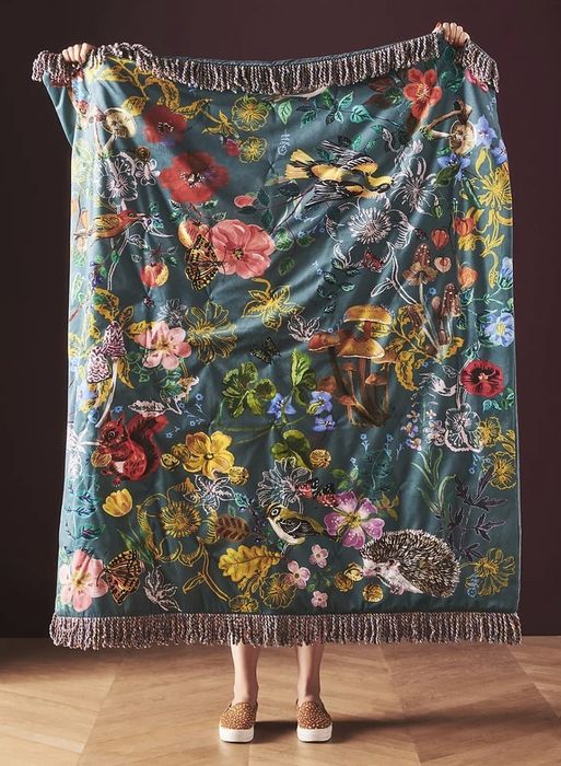 Someone holding up the blanket with tasseled fringes