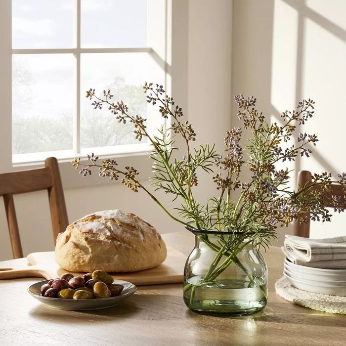 The green vase filled with flowers, adding a refreshing touch to the table.