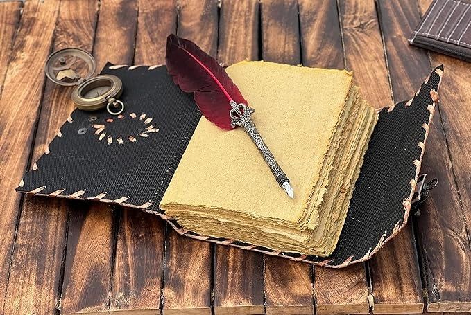 A vintage-themed notebook paired with a feather pen and compass, elegantly arranged on a weathered wooden table