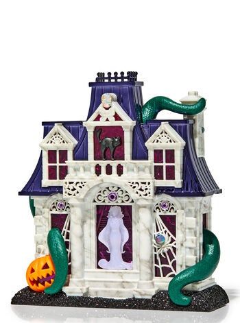 A Halloween-themed ceramic haunted house adorned with a black cat, a jack-o'-lantern, and green tentacles winding around the structure