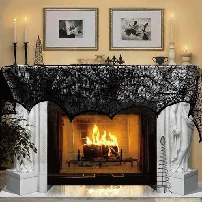 A fireplace adorned with black lacey cobweb-style decor elegantly draped across the mantel