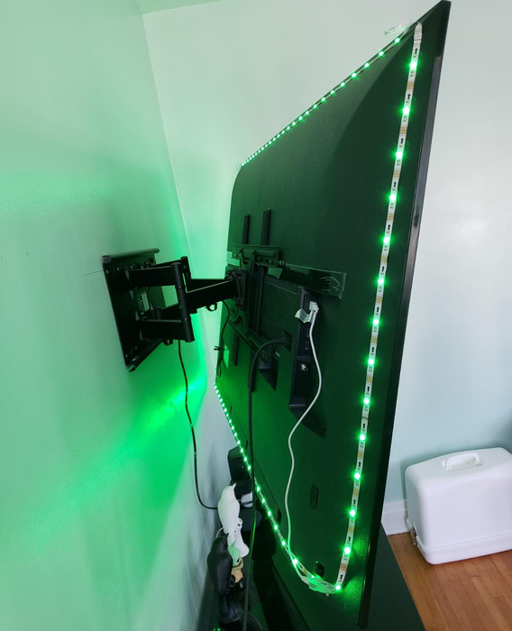 A reviewer showcasing the back of their TV, featuring the LED light strip attached, enhancing the ambiance.