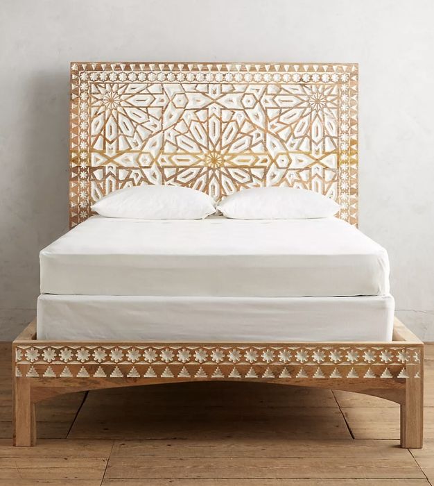 The wooden bed with a mattress placed on top, ready for rest.