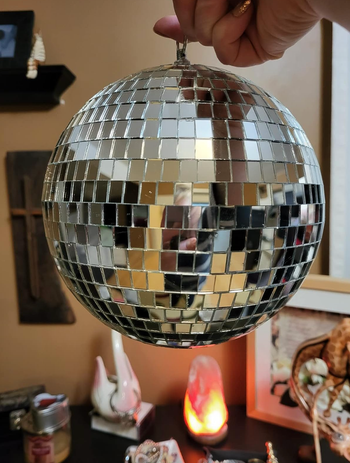 A reviewer holding a small disco ball in hand, ready to add a sparkle to any space.