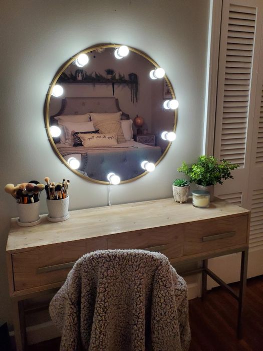 A reviewer's round vanity mirror, beautifully surrounded by string lightbulbs, creating a chic glow.