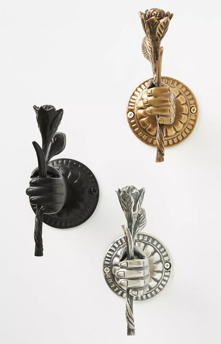 The elegant gold, black, and silver hooks mounted on the wall, offering a chic and practical solution for hanging.
