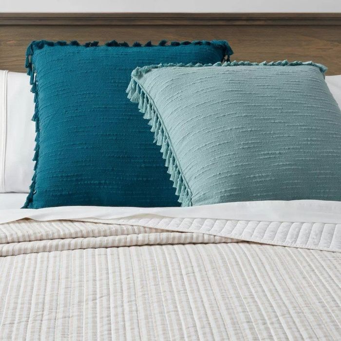 Two blue tassel pillows on a bed