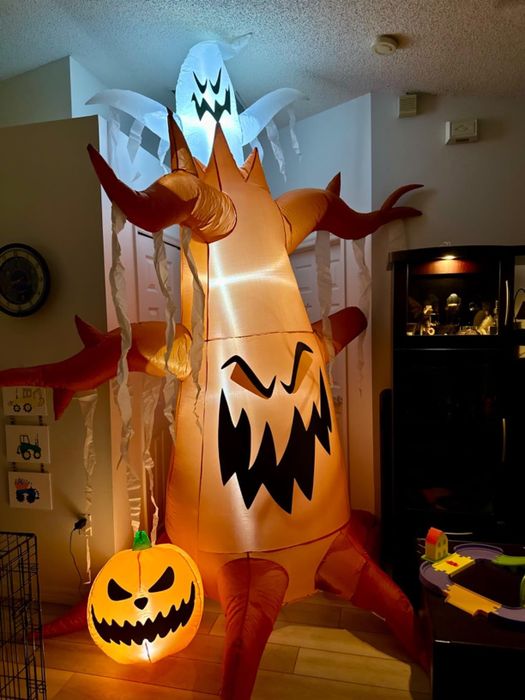 An indoor Halloween inflatable featuring a menacing tree, a jack-o'-lantern, and a ghost, all with eerie expressions
