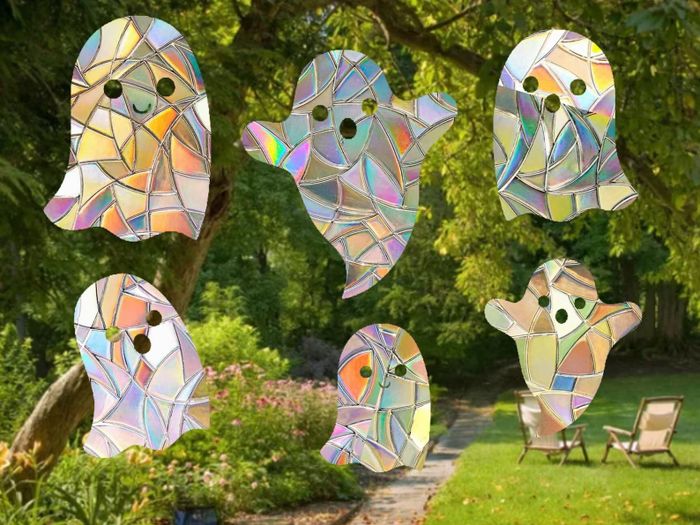 Six holographic stained-glass ghost ornaments hanging in a garden, with trees, flowers, and lawn chairs in the background