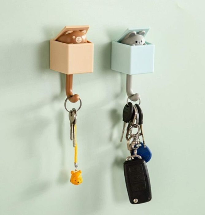 Two cat-shaped hooks on a wall, each holding a set of keys.