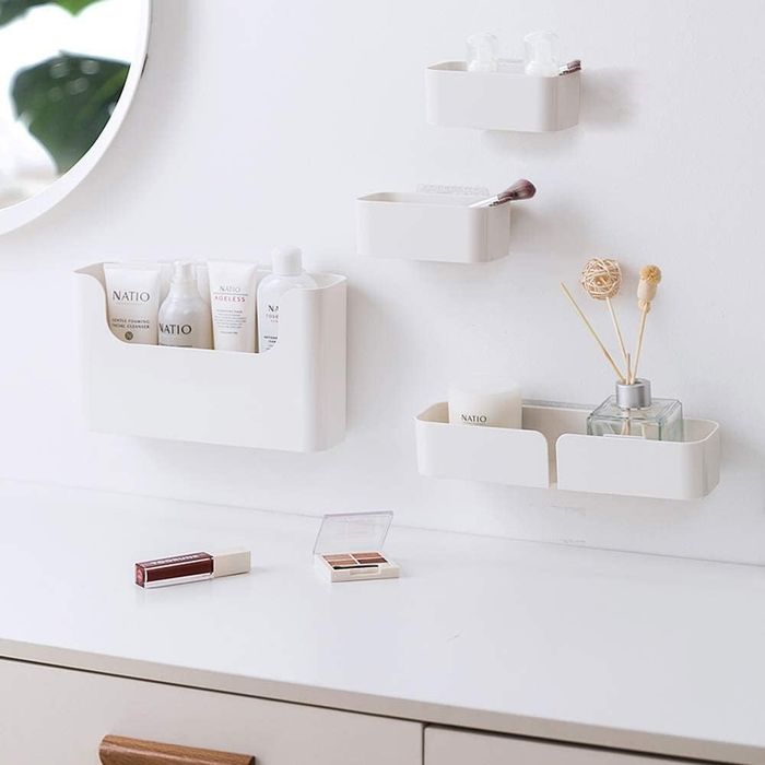 Four differently sized shelves mounted on the wall, holding various bathroom essentials