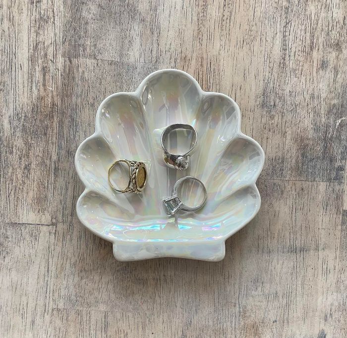 A reviewer’s white shell trinket dish, holding a selection of rings inside, adding a delicate touch to their vanity.
