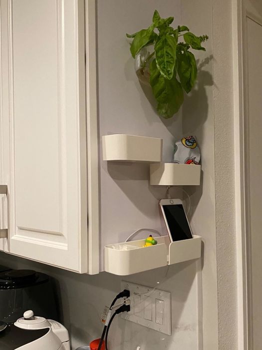 A reviewer’s photo showing three shelves attached to the side of a white cabinet, holding a phone and other small trinkets