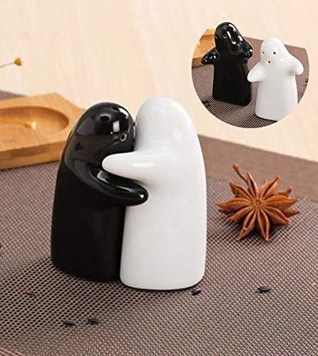 Two ceramic salt and pepper shakers, one black and one white, hugging on a table surrounded by spices