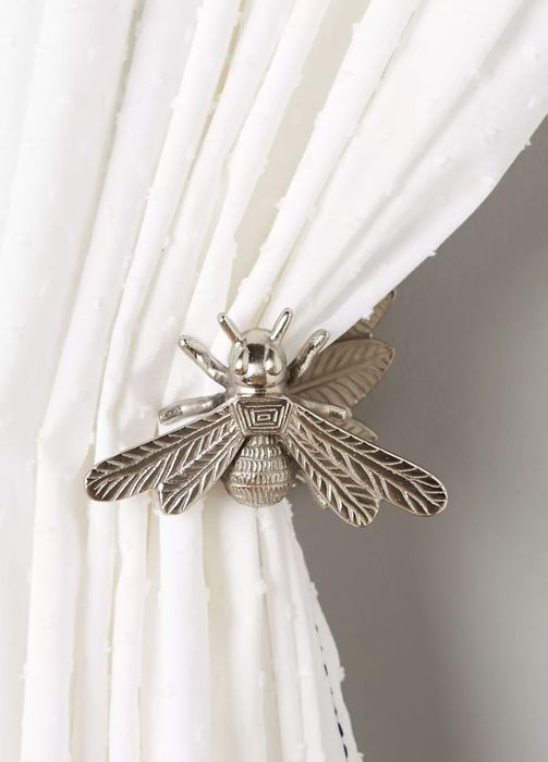 The silver bee elegantly holding back a crisp white curtain