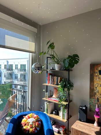 A disco ball hanging in a bedroom, casting shimmering light reflections on the walls.