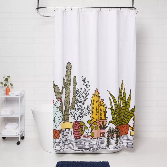 The white shower curtain adorned with colorful succulents at the bottom half