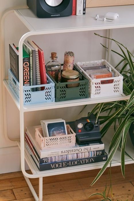 The blue, green, white, and pink storage organizers neatly arranged on a shelf, each one filled with small items like books, photos, and candles.