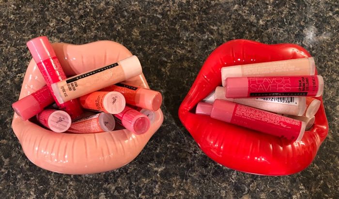 Two lip-shaped containers, one in pink and the other in red, filled with lip balms neatly tucked inside.