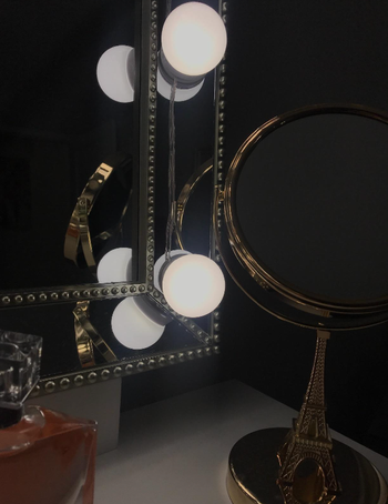 A close-up of the string lights on a reviewer's mirror, adding a warm, stylish touch to the space.