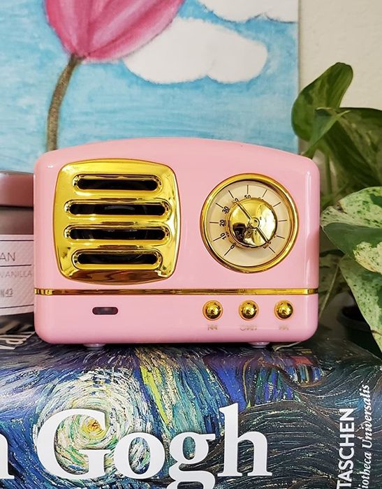 A reviewer's image of a small pink retro Bluetooth speaker, capturing its compact and stylish design.
