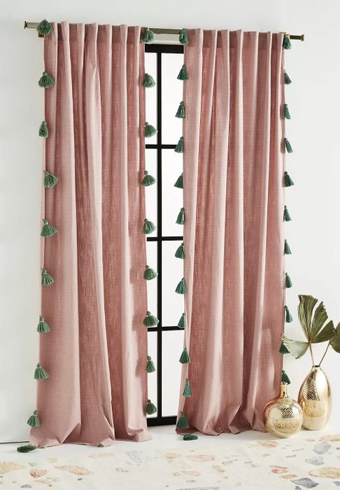 The pink curtains with teal tassels hanging gracefully on the window