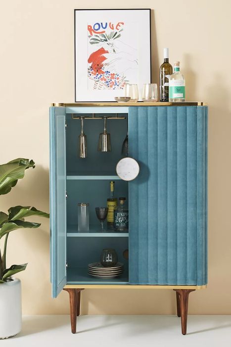 The blue bar cabinet with one door swung open, showcasing its sleek interior.