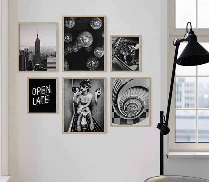 A gallery wall featuring a collection of framed photographs, including cityscapes and celestial imagery, placed next to a window.