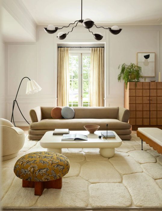 A chic living room featuring a blend of modern furniture, including a sofa, chairs, and a quirky, eclectic stool that adds character to the space.