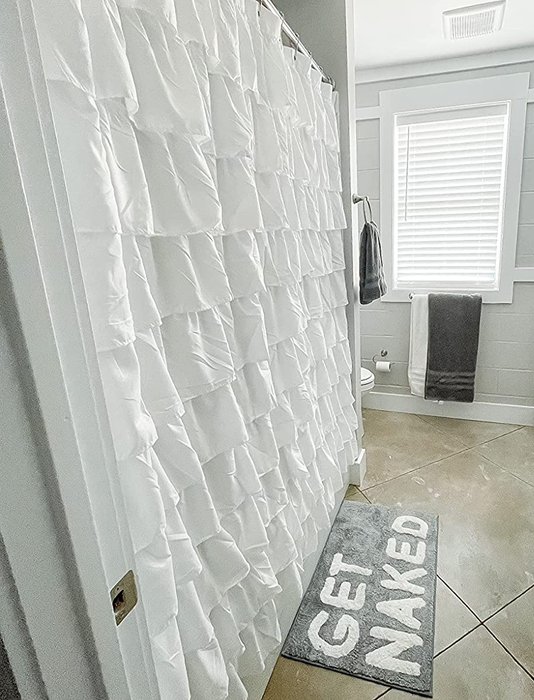 A side-view reviewer photo of the white ruffled shower curtain in their bathroom.