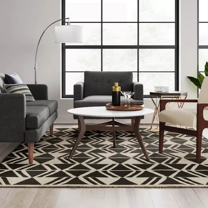 Contemporary living room featuring a geometric rug, grey sofa, white coffee table, and gold accent pieces