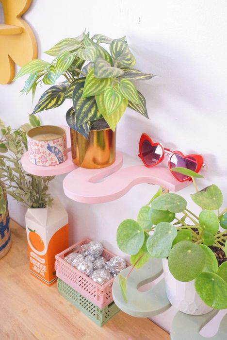A close-up of a stylish pink shelf, adorned with plants and sunglasses, adding a touch of whimsy to the space.