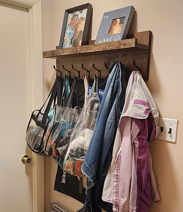 Reviewer photo showing the wooden coat rack with jackets and bags hanging from it.